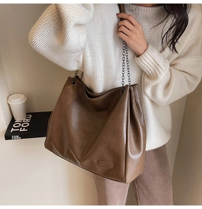 Dettaglio borsa tote marrone vintage con tracolla a catena su modella con maglia bianca