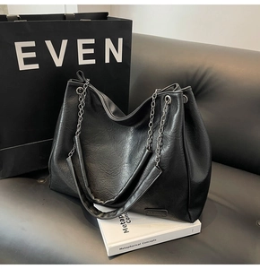Dettaglio della borsa tote nera con tracolla a catena e patch logo alla moda