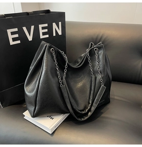 Dettaglio della borsa tote in pelle nera con tracolla a catena argento e texture plissettata