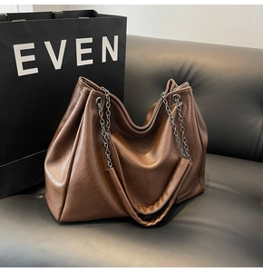 Dettaglio di una grande borsa tote marrone con texture in pelle e catena