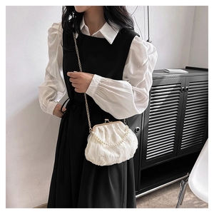 Detail of white lace cloud bag featuring pearl handle and gold chain strap