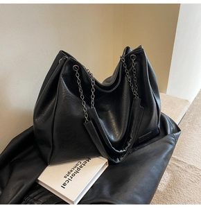 Dettaglio della borsa tote nera con tracolla a catena argentata e logo Fashion