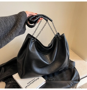 Dettaglio della grande borsa tote in pelle nera con tracolla a catena e grana fine