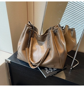 Dettaglio di una borsa tote in pelle PU kaki con catena ed etichetta moda su uno scaffale