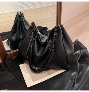 Dettaglio borsa hobo nera con trama a grana litchi e tracolla a catena in metallo
