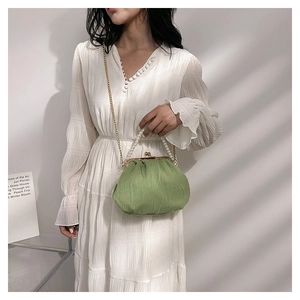 Detail of green ruched cloud bag featuring pearl handle and golden chain strap