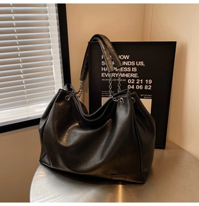 Dettaglio della trama in pelle PU nera con elegante chiusura a pieghe sulla borsa tote