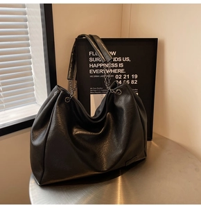 Dettaglio della borsa tote in pelle nera a pieghe con tracolla a catena metallica
