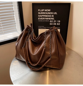 Dettaglio della borsa tote marrone in pelle PU con tracolla a catena d'argento e patch