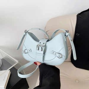 Light blue faux leather half-moon bag with silver studs and adjustable straps