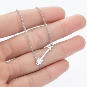 Detailed view of a silver arrow pendant necklace held in hand to show size and texture