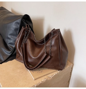 Dettaglio ravvicinato della borsa tote in pelle marrone scuro con tracolla a catena