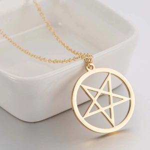 Minimalist gold circle star pendant necklace displayed on a white ceramic bowl