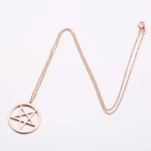 Macro detail of rose gold pentagram pendant with cross chain and lobster clasp