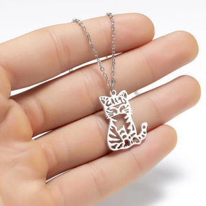 Detailed view of silver hollow cat pendant on stainless steel chain held by hand