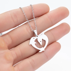 Detailed view of silver heart-shaped dolphin hollow pendant held in hand for scale