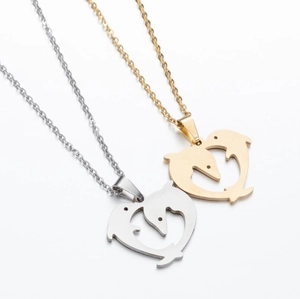Close-up of gold and silver dolphin heart pendants on stainless steel chains