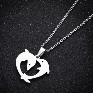 Detailed view of silver dolphin heart pendant necklace on shimmering black background