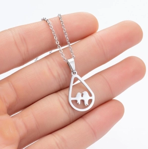 Detailed view of hollow teardrop pendant with birds on branch in stainless steel