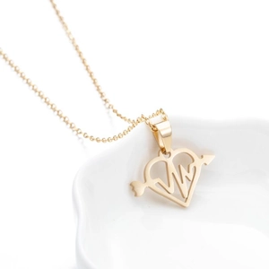 Macro shot of gold-plated heart and pulse line pendant necklace on a white ceramic plate