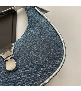 Close-up of vintage denim baguette bag with silver metallic trim and buckle closure