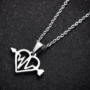 Macro shot of silver stainless steel heart and arrow pendant on sparkling black background