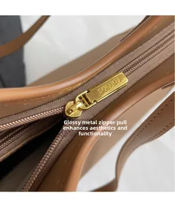 Detail of gold zipper hardware with engraved logo on brown leather tote bag