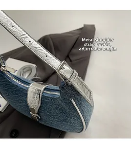 Close-up of denim baguette bag with adjustable silver hardware and metallic shoulder strap