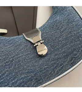 Detail of dark blue denim fabric with premium silver metal buckle on a baguette bag