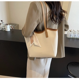 Detail of cream pebbled leather tote bag with brown handles and a patterned silk scarf