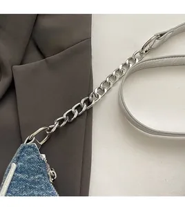 Detail of premium denim fabric texture with shiny silver metal chain strap and hardware