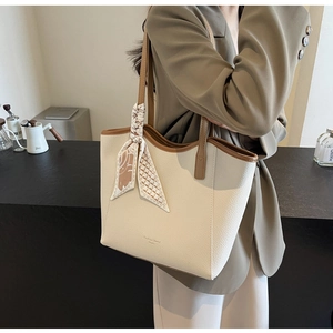 Detail view of large cream tote bag with brown leather trim and floral silk scarf
