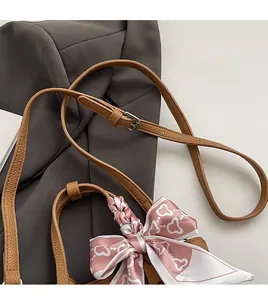 Detail of brown lychee leather bucket bag with silk scarf bow and adjustable strap