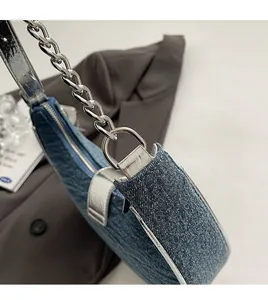 Close-up of premium silver chain hardware and blue denim fabric on the saddle bag