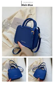Detail showing Klein Blue square handbag with golden FASHION & BAGS lettering and hardware