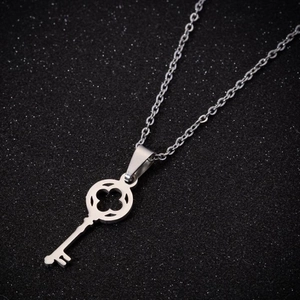Minimalist silver stainless steel key pendant necklace with clover cutout on black base
