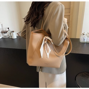Close-up of khaki pebbled leather tote bag with decorative floral scarf on a model