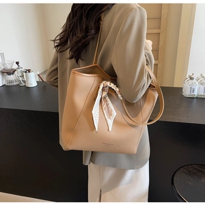 Detail of tan lychee grain tote bag with silk scarf handle in cafe setting