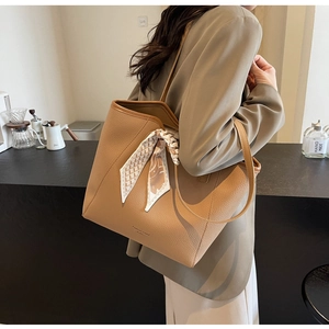 Close-up of caramel brown leather tote bag with lychee texture and floral silk scarf