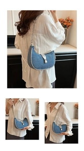 Detail view of denim baguette bag with silver chain strap and metal buckle closure