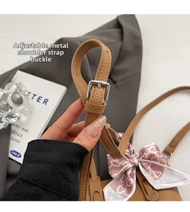 Detail of adjustable leather strap and silver buckle on brown bucket bag with silk scarf