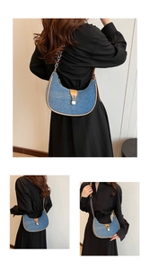 Detail showing blue denim half-moon bag with leather strap and silver chain link