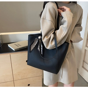 Detailed shot of black pebbled leather tote bag with geometric silk scarf on shoulder strap