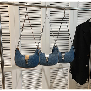 Three vintage denim baguette bags in brown, silver and black leather trim hanging