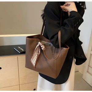 Detail of dark brown tote bag with silk scarf on shoulder of model in business attire