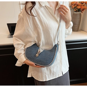 Detailed shot of a crescent denim hobo bag with silver metallic trim and buckle