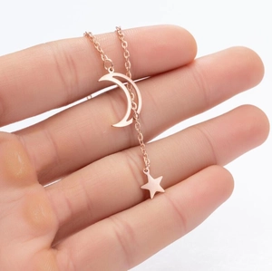 Detail shot of rose gold necklace featuring textured moon and star pendants with thin chain