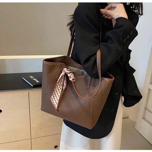Brown lychee leather tote bag with silk scarf detail shown on shoulder for daily commute