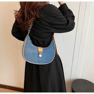 Blue denim crescent bag with metallic chain and brown leather trim shown on model