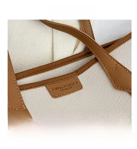 Macro shot of litchi grain leather texture and reinforced stitching on a contrast tote bag
